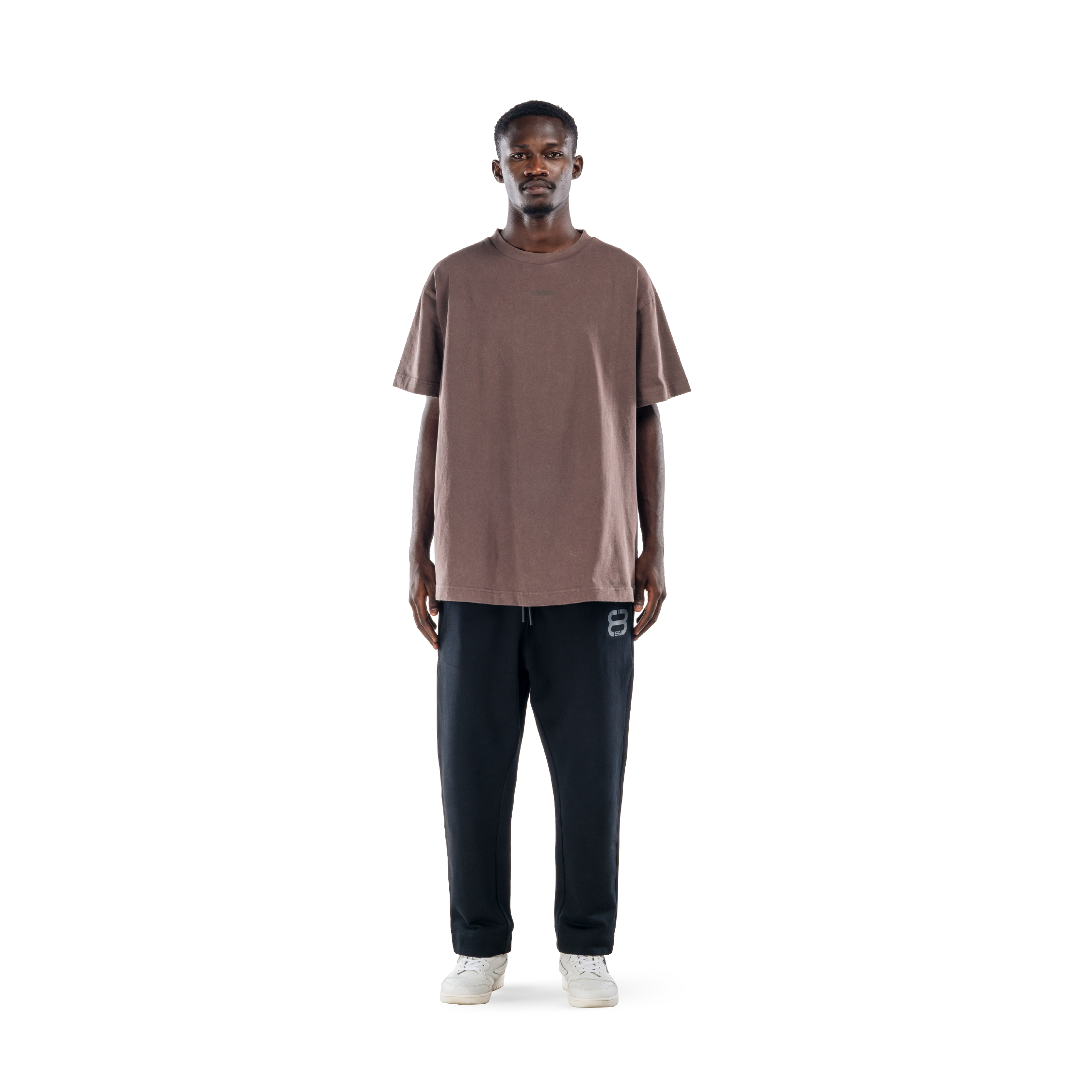 model wears ash brown t-shirt with black sweatpants and white shoes. front view.
