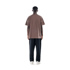 model wears ash brown t-shirt with black sweatpants and white shoes. back view.