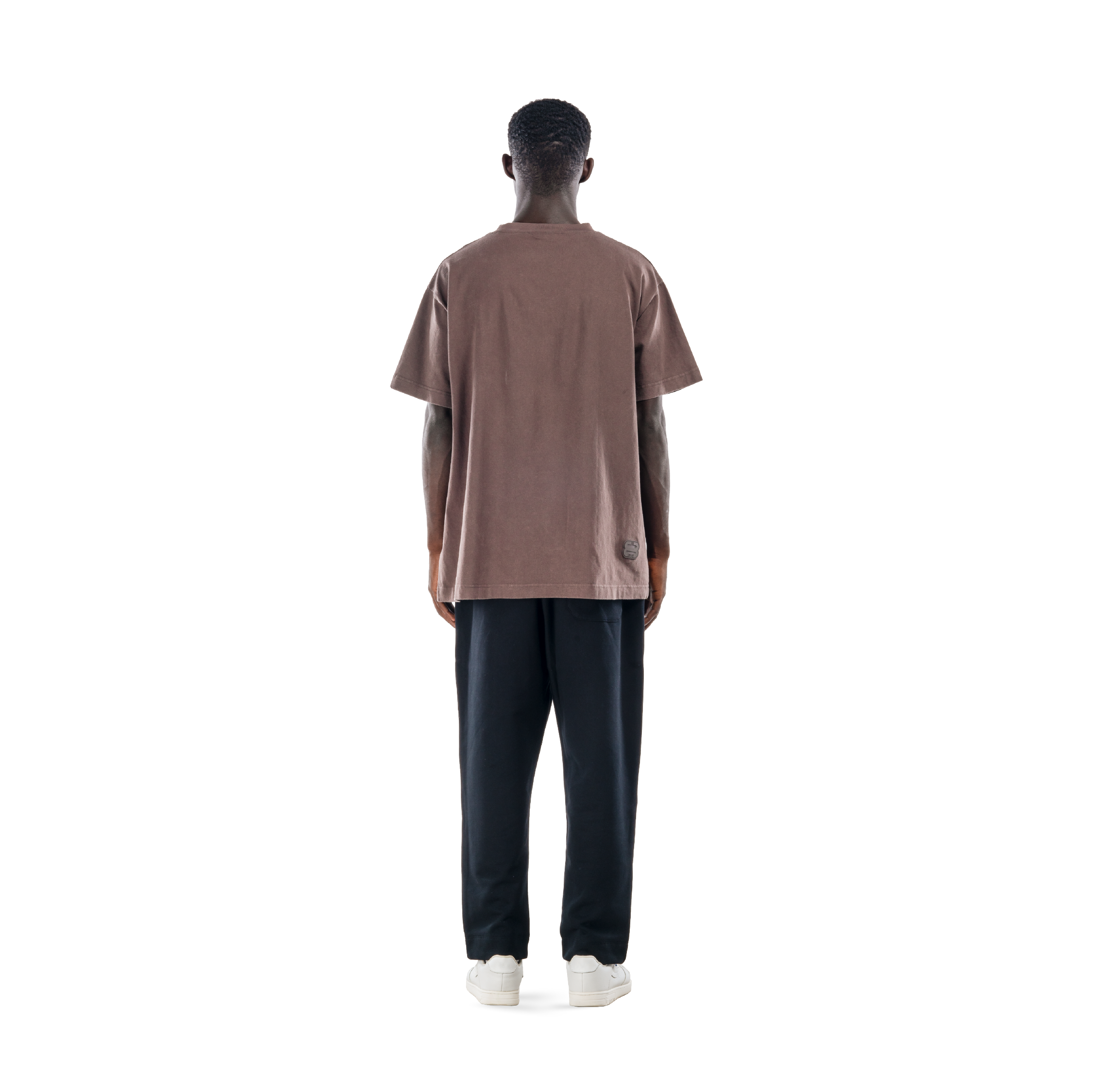 model wears ash brown t-shirt with black sweatpants and white shoes. back view.