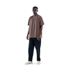 model wears ash brown t-shirt with black sweatpants, black glasses and white shoes. front view.