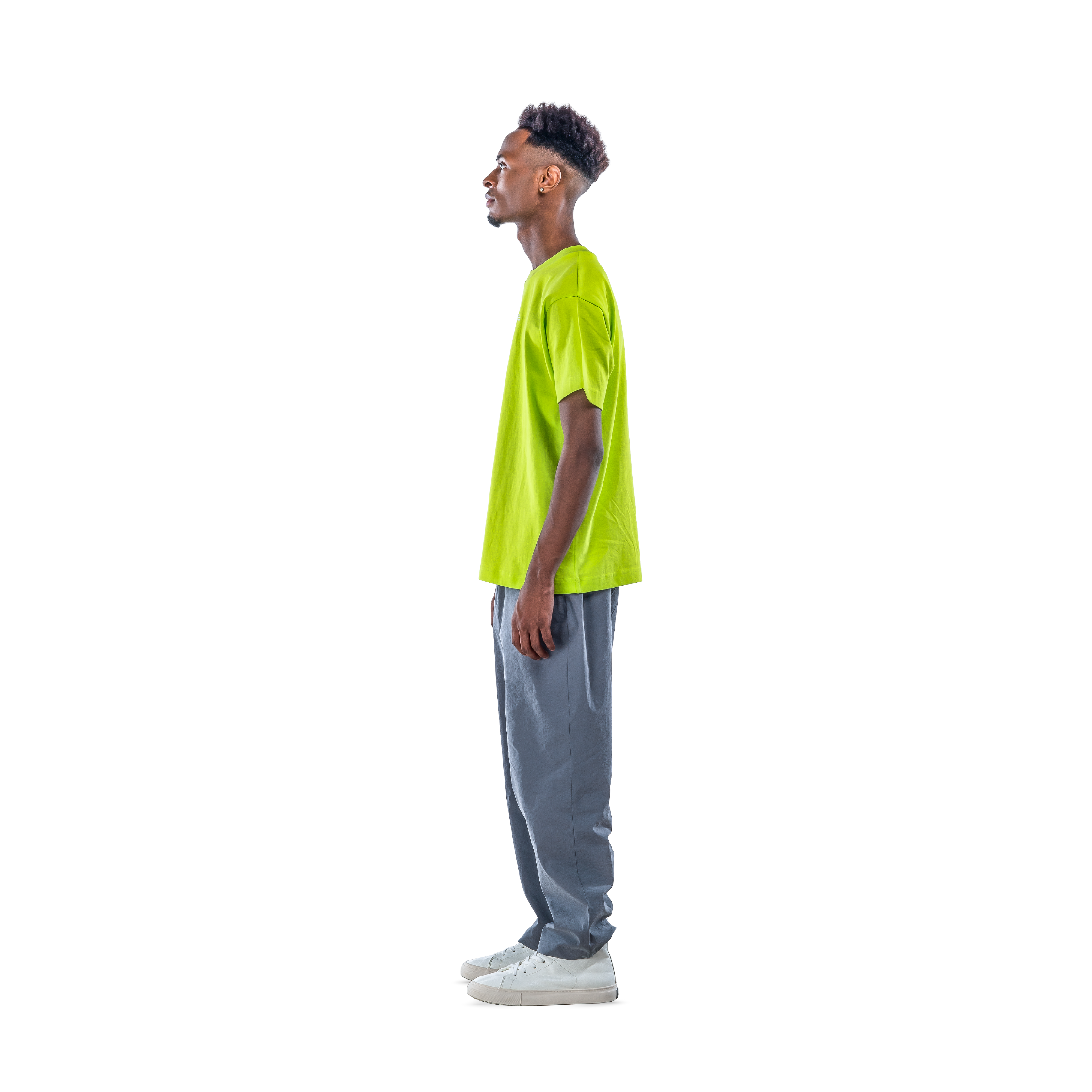model wears neon green t-shirt with black sweatpants and white shoes. side view.