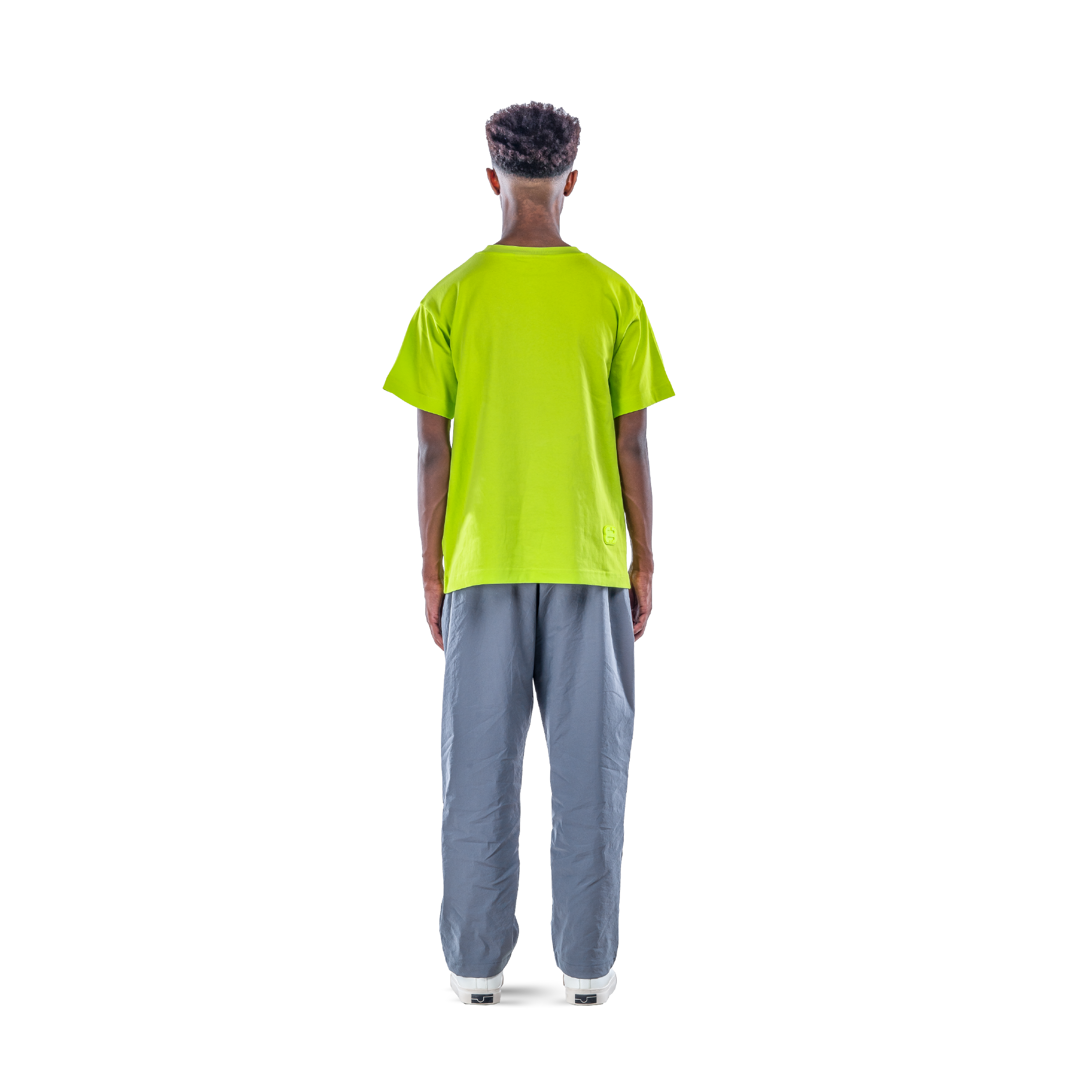 model wears neon green t-shirt with black sweatpants and white shoes. back view.