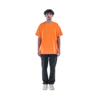 model wears orange t-shirt with black sweatpants and white shoes. front view.