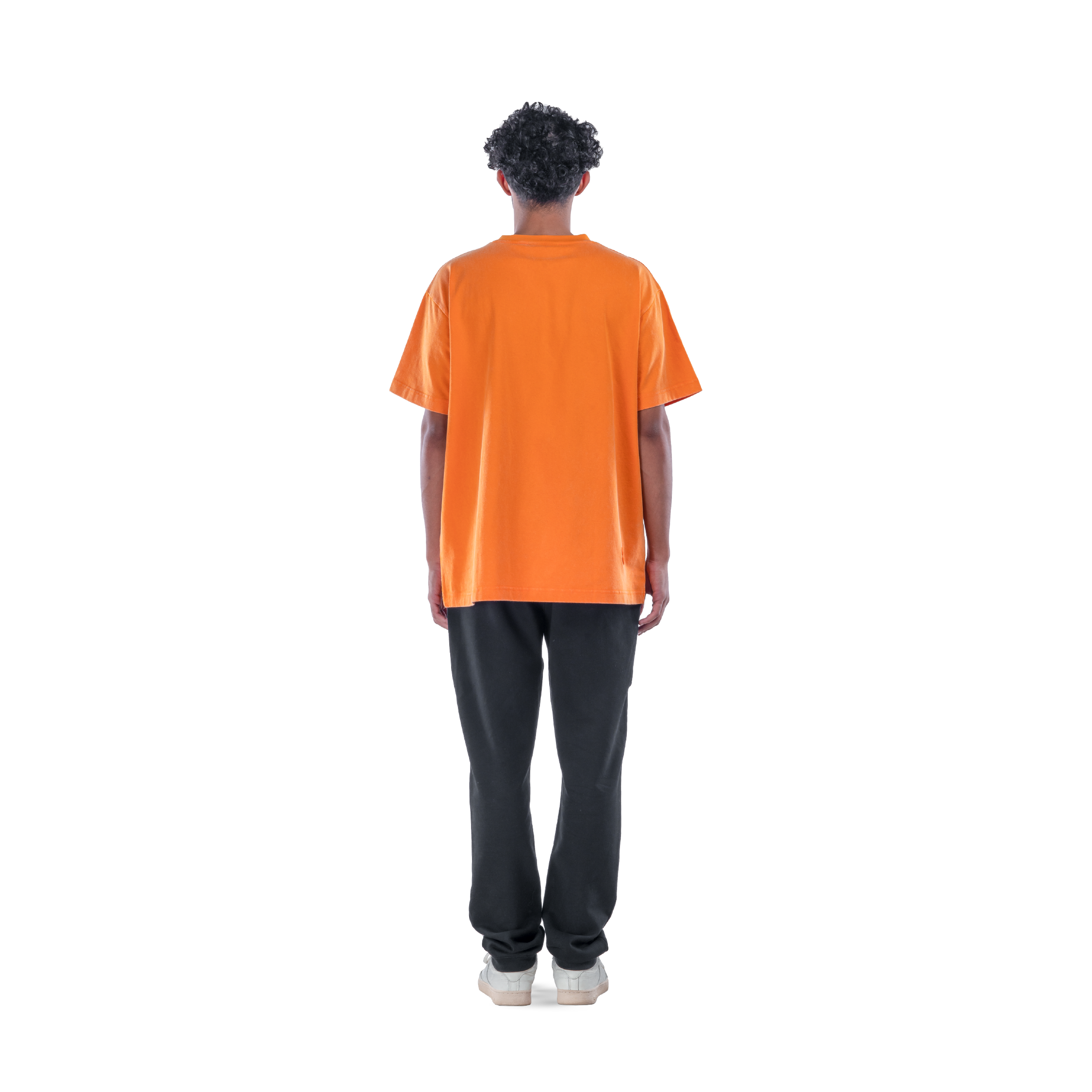 model wears orange t-shirt with black sweatpants and white shoes. back view.