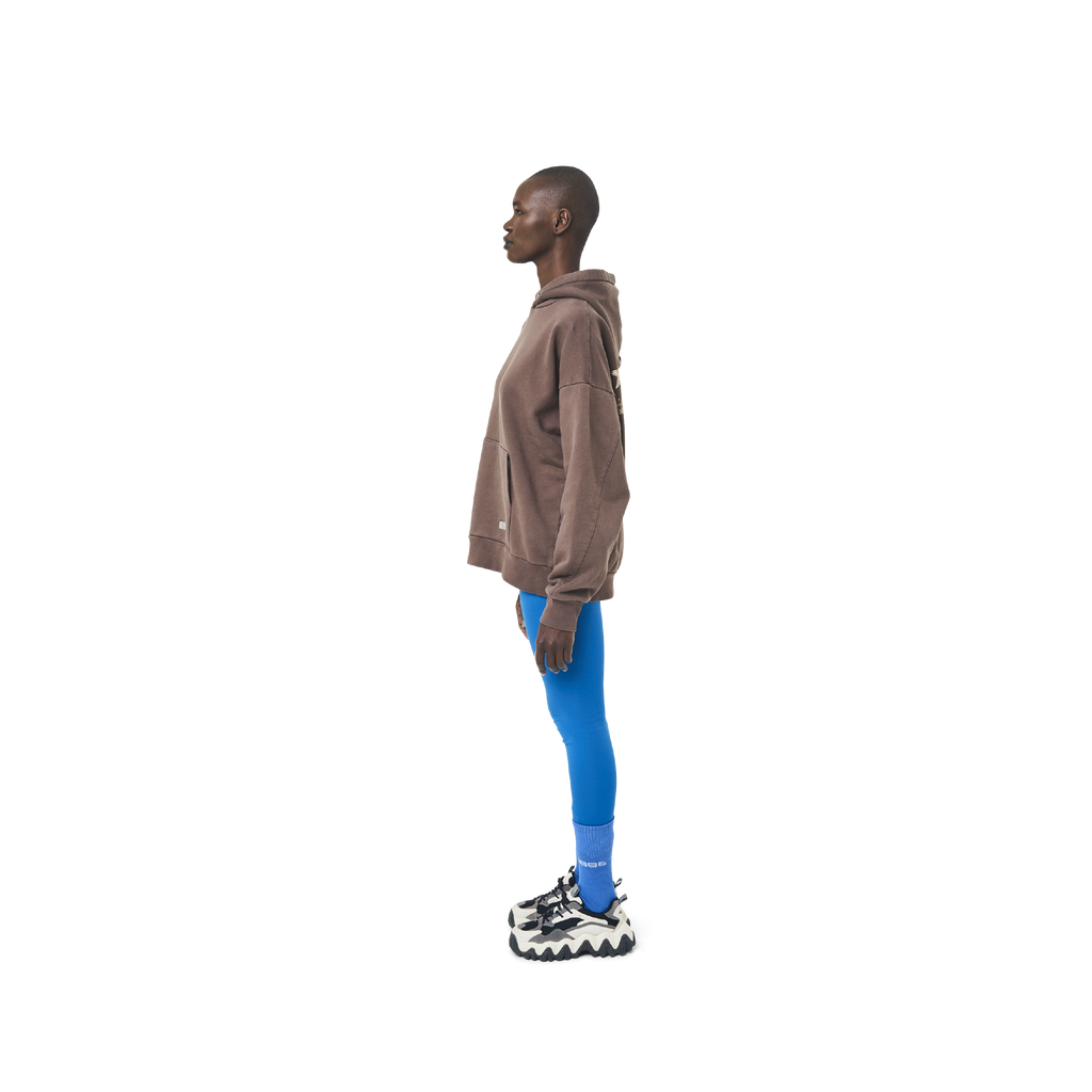 Long sleeves oversize cut hoodie in washed brown color fabric featuring 1886 print at back. 1886 logo embroidered at kangaroo pocket. A button on the hood. Rib knit at cuffs and hem